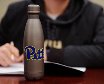 Student at desk with Pitt water bottle